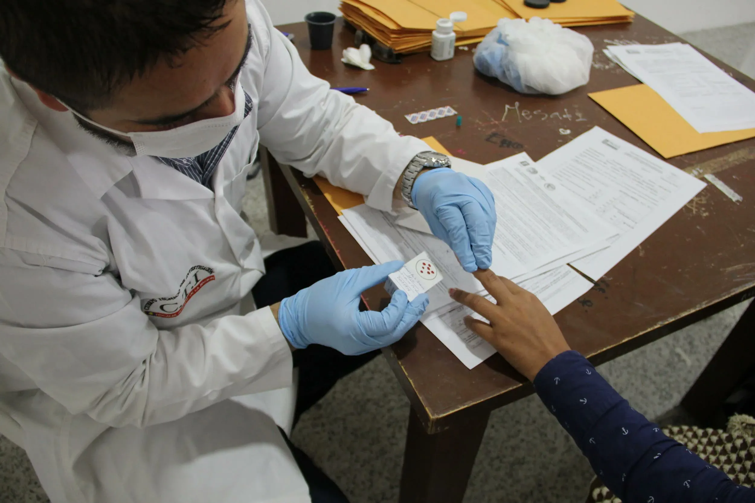 A forensic technician takes a blood sample from a woman looking for her missing father in Sogamoso, Colombia.
